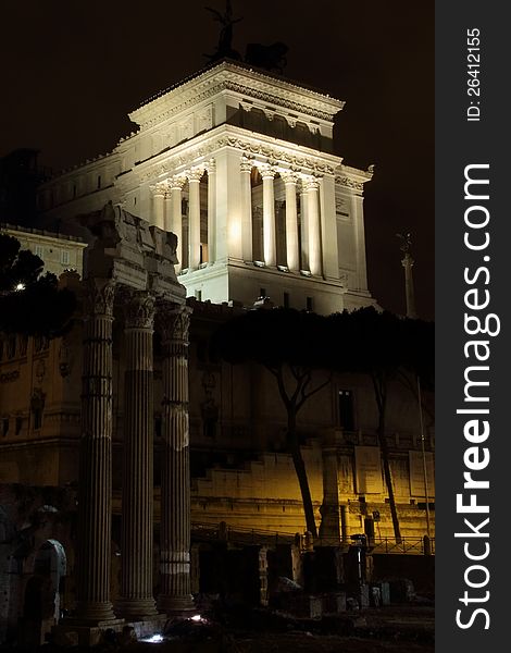 Monumento nazionale a vittorio emanuele II with the temple of vespasian in the foreground at night with black skies rome