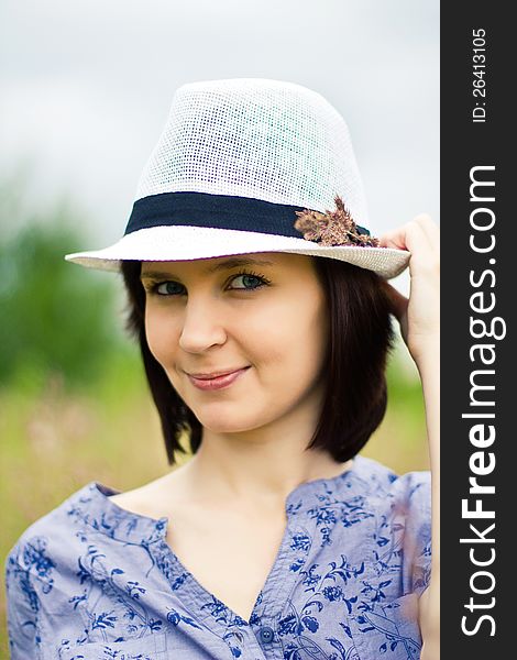 Beautiful young brunette woman in straw hat on the meadow