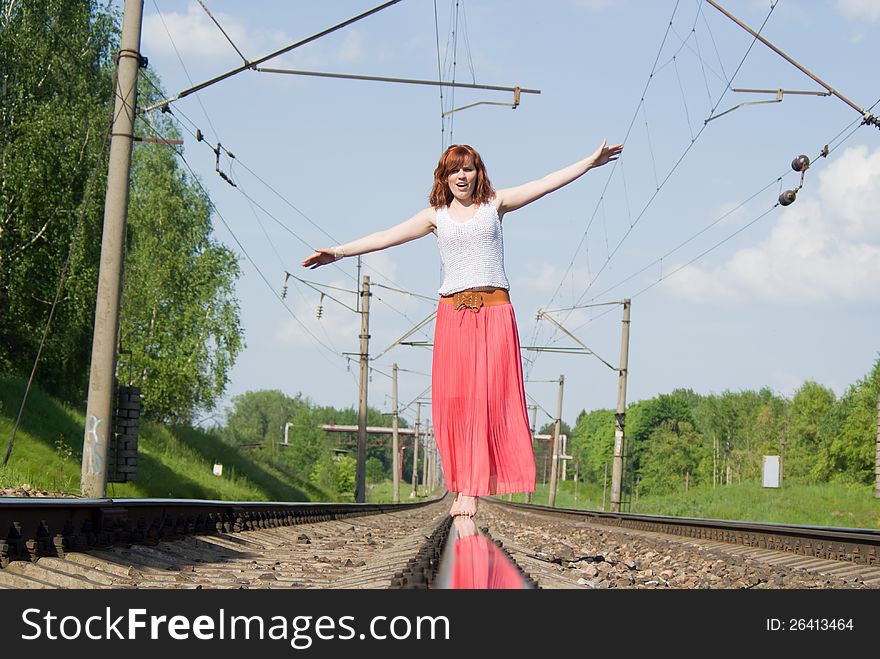 Beautiful girl standing on the rails on nature