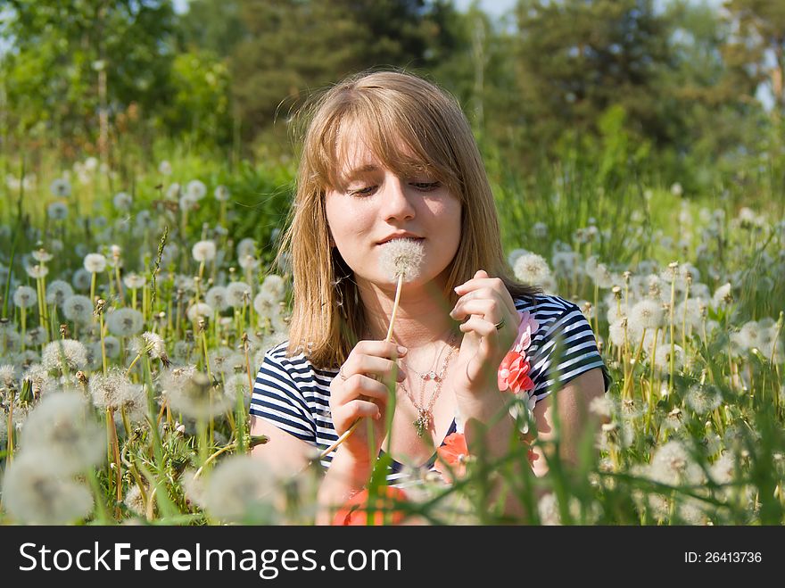 Beautiful girl lying on the field in dandelion on nature