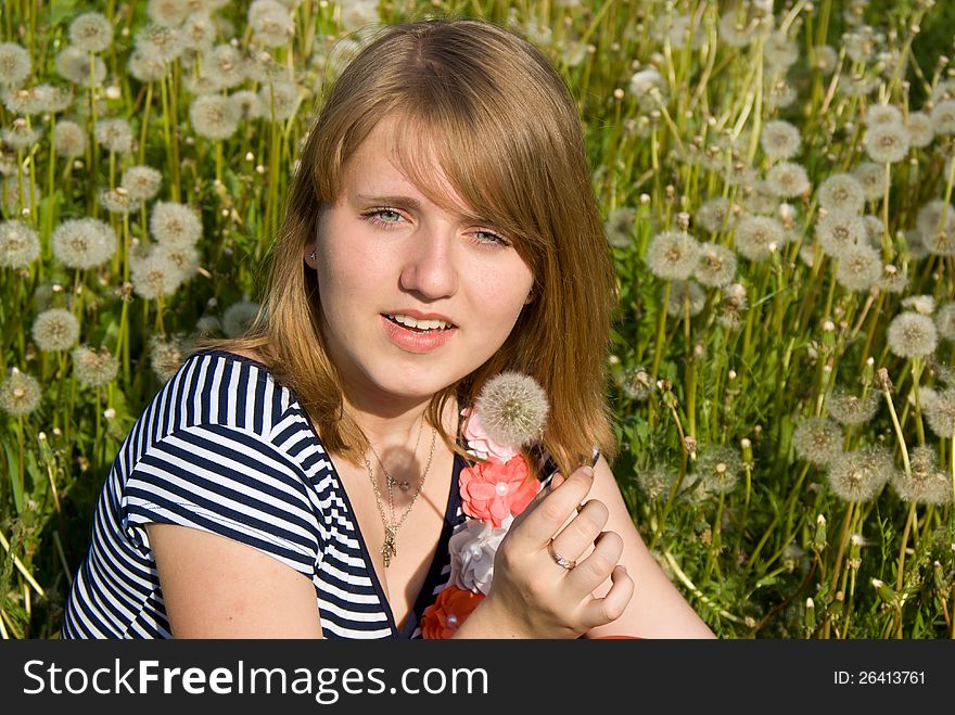 Beautiful girl lying on the field in dandelion on nature