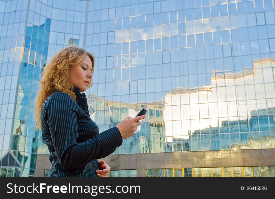 Young attractive businesswoman talking on mobile phone opposite office building