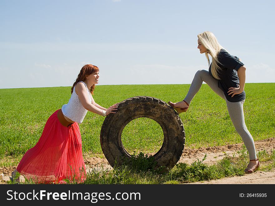 Two girls rolls wheel on the nature