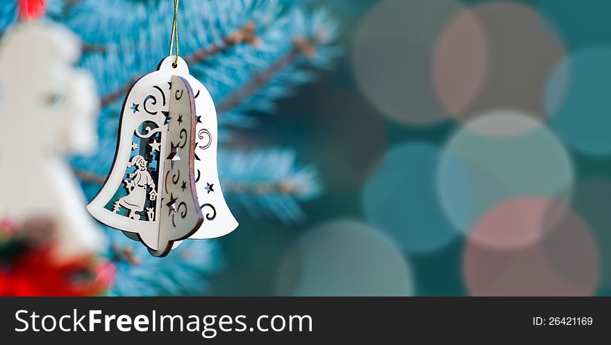 Christmas decoration of woody angel and handmade bell on the blue background of fir-tree having much space for text. Christmas decoration of woody angel and handmade bell on the blue background of fir-tree having much space for text