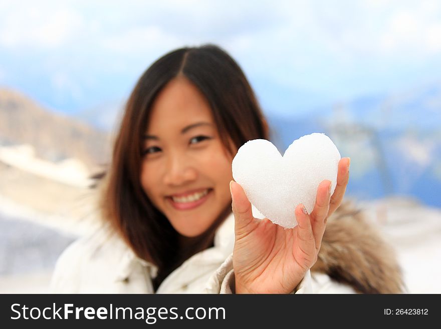 Asian woman holding a snowball with a shape of heart