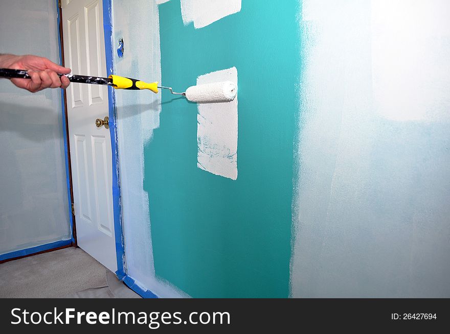 An image of a green wall being painted white