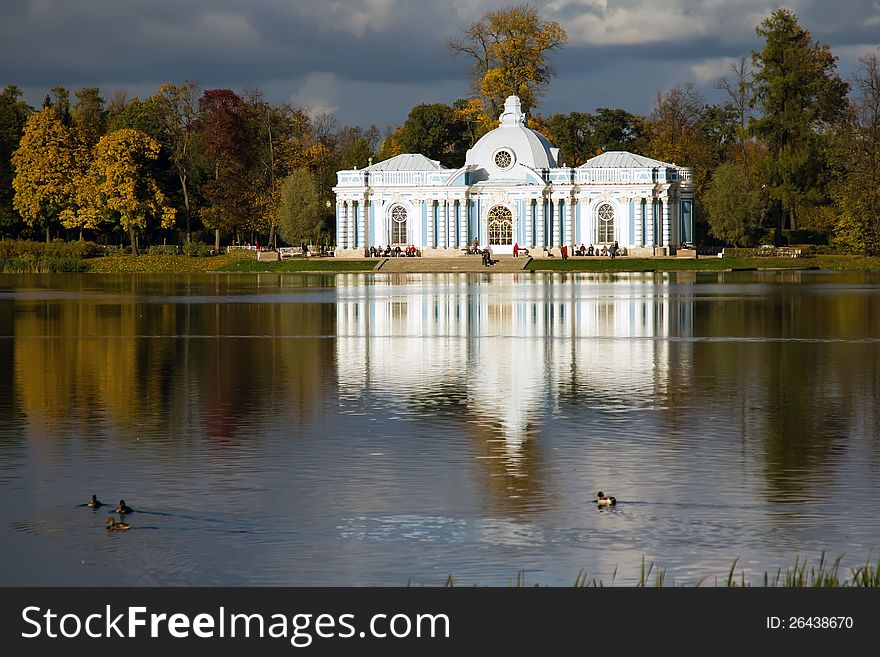 The historic building behind the lake with birds is reflected in water. The historic building behind the lake with birds is reflected in water