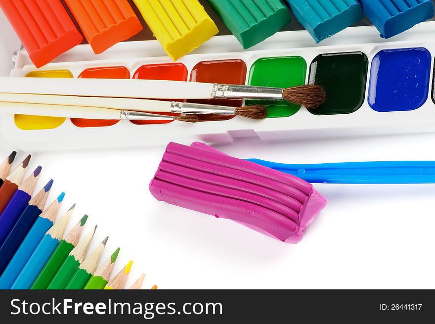 Arrangement of Clay, Paint Brushes, Color Pencils and Watercolor Paints isolated on white background. Arrangement of Clay, Paint Brushes, Color Pencils and Watercolor Paints isolated on white background