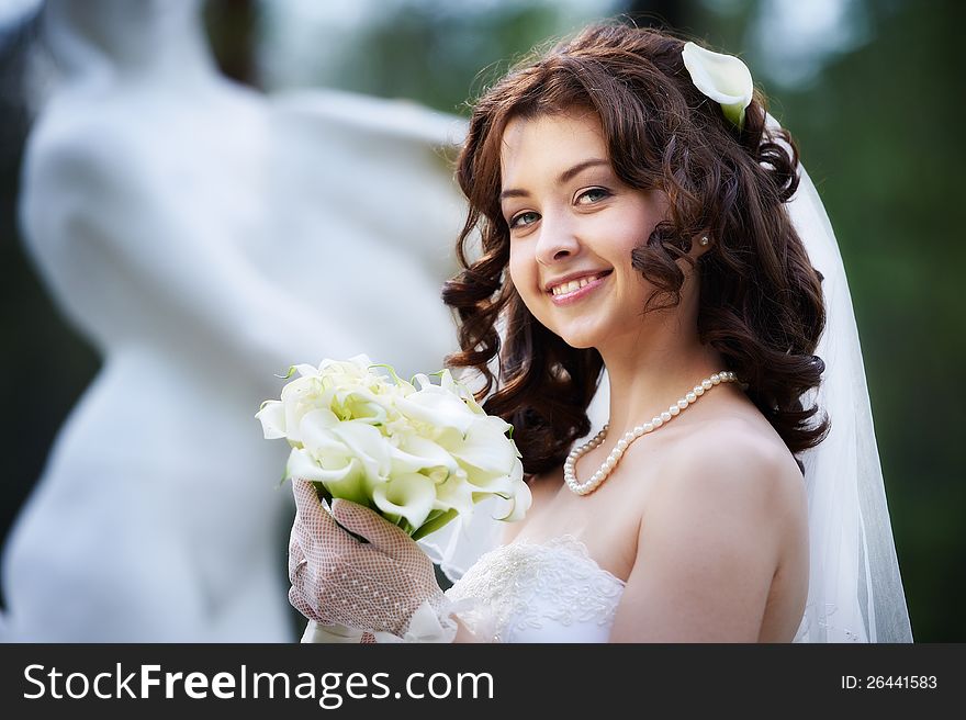 Happy bride with white wedding bouquet on blurred background