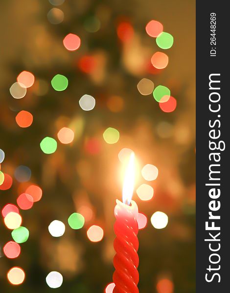 A red Christmas candle with a background of out-of-focus Christmas tree tree lights