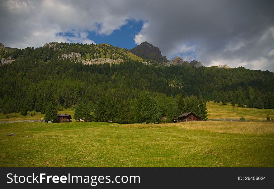 A landscape view of Dolomiti with rustic cottages in San Pellegrino pass (Alps) Italy. A landscape view of Dolomiti with rustic cottages in San Pellegrino pass (Alps) Italy.
