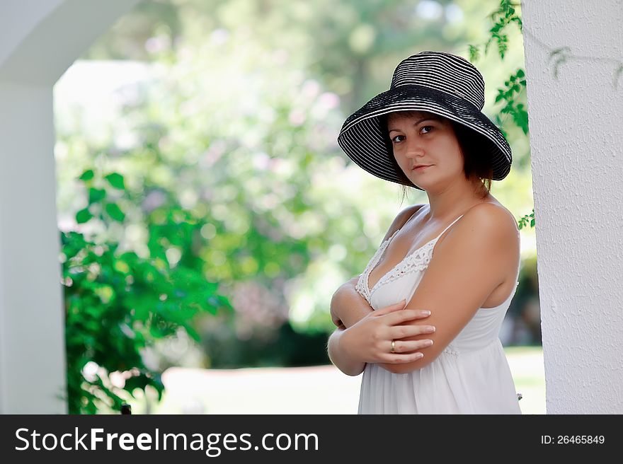 Girl in a white dress and black hat posing under the arch. Girl in a white dress and black hat posing under the arch