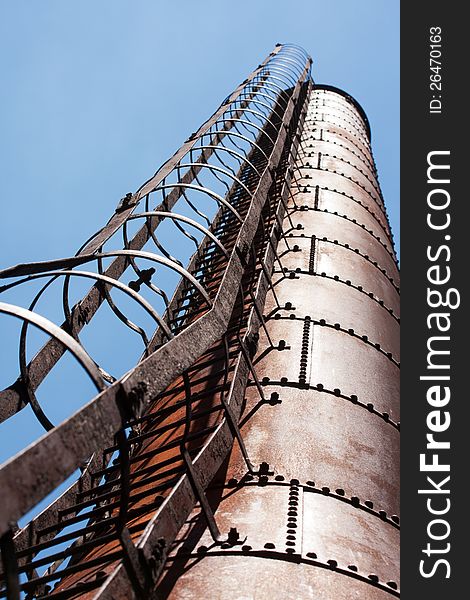 Industrial factory chimney with ladder against blue sky. Industrial factory chimney with ladder against blue sky