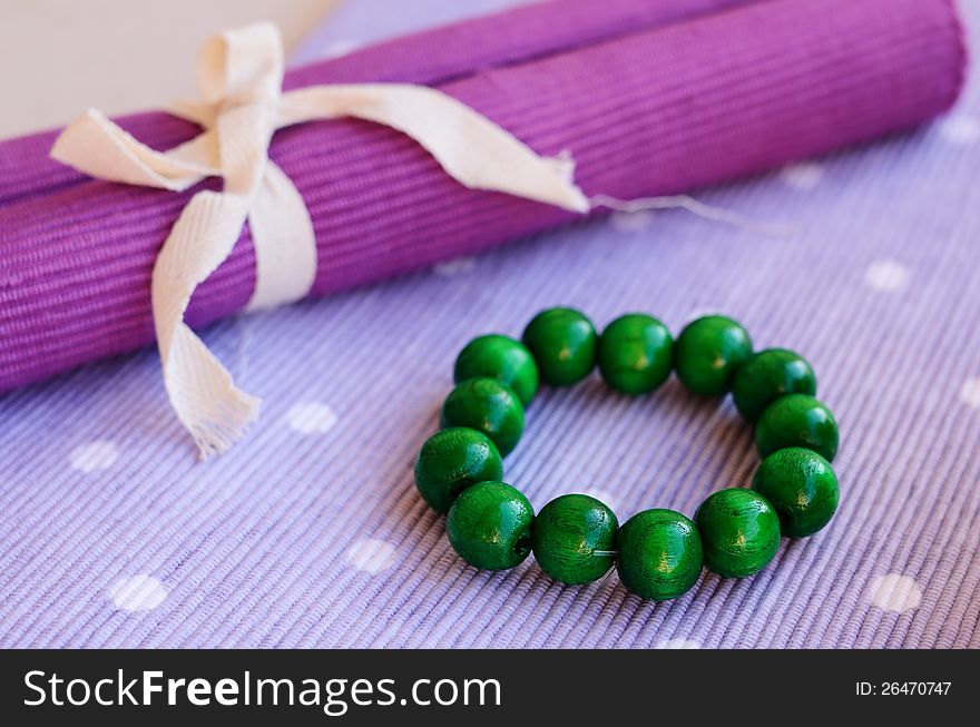 Green wooden bracelet laying on lavender table napkin