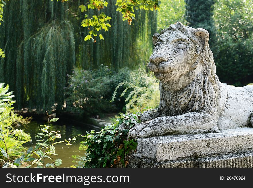 Stone sculpture of lion in green park area. Stone sculpture of lion in green park area