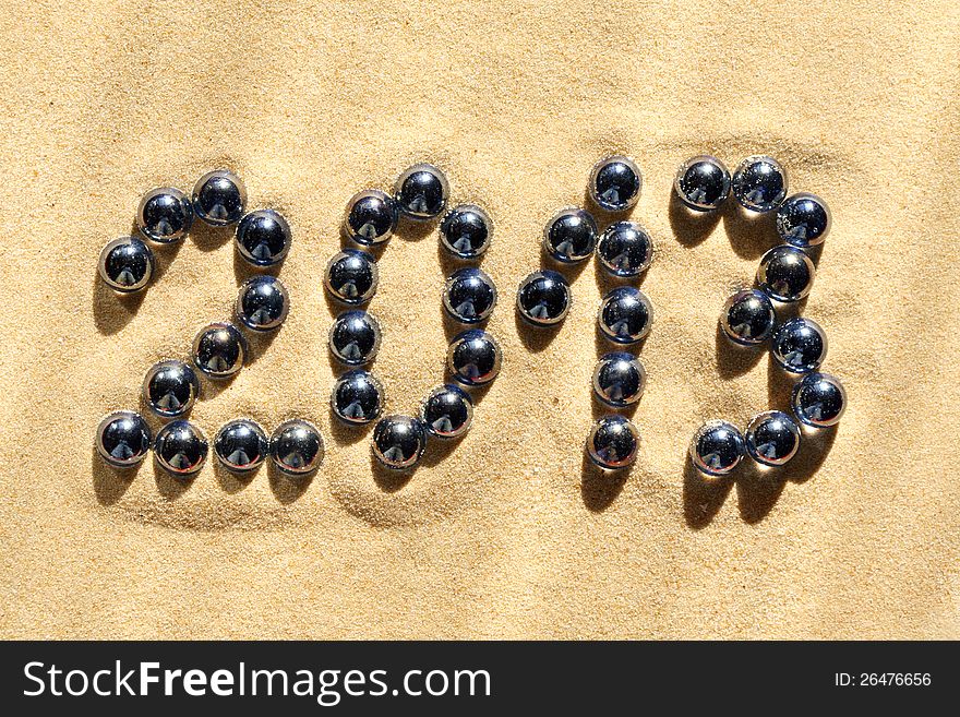 2013 inscription made from glass balls lying on sand surface