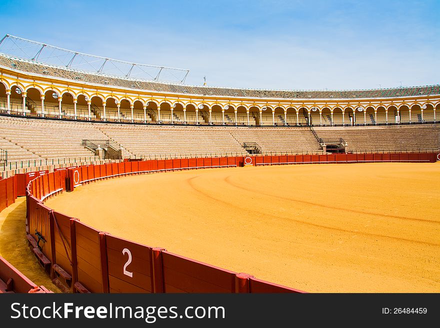 The bullring in Seville, Spain, showing the stands and the sandy ring, ready for a fight. There are no people and there is copy space. The bullring in Seville, Spain, showing the stands and the sandy ring, ready for a fight. There are no people and there is copy space.