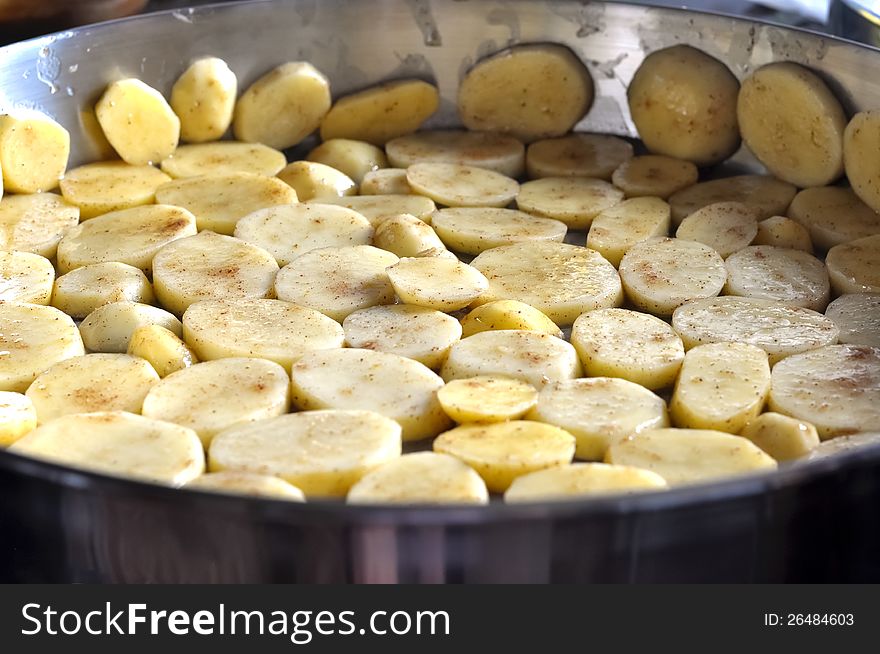 Sliced potatoes in a cooking pan that are being cooked. Sliced potatoes in a cooking pan that are being cooked