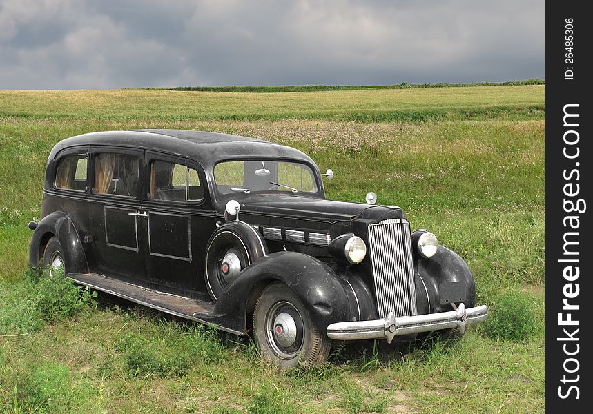 Vintage old black automobile hearse, sitting in a mid-west country pasture, with dark storm clouds in the background. Vintage old black automobile hearse, sitting in a mid-west country pasture, with dark storm clouds in the background.