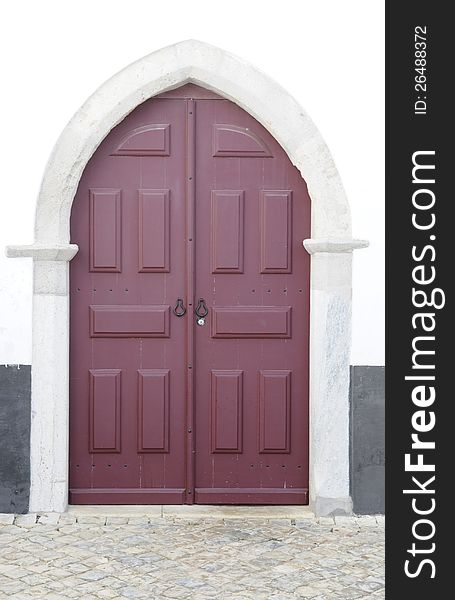 Exterior double wooden door from a little church, Algarve, Portugal. Stone arched jamb.