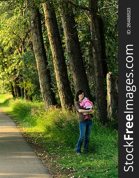 Young mother holding her baby daughter in an outdoor park. Young mother holding her baby daughter in an outdoor park