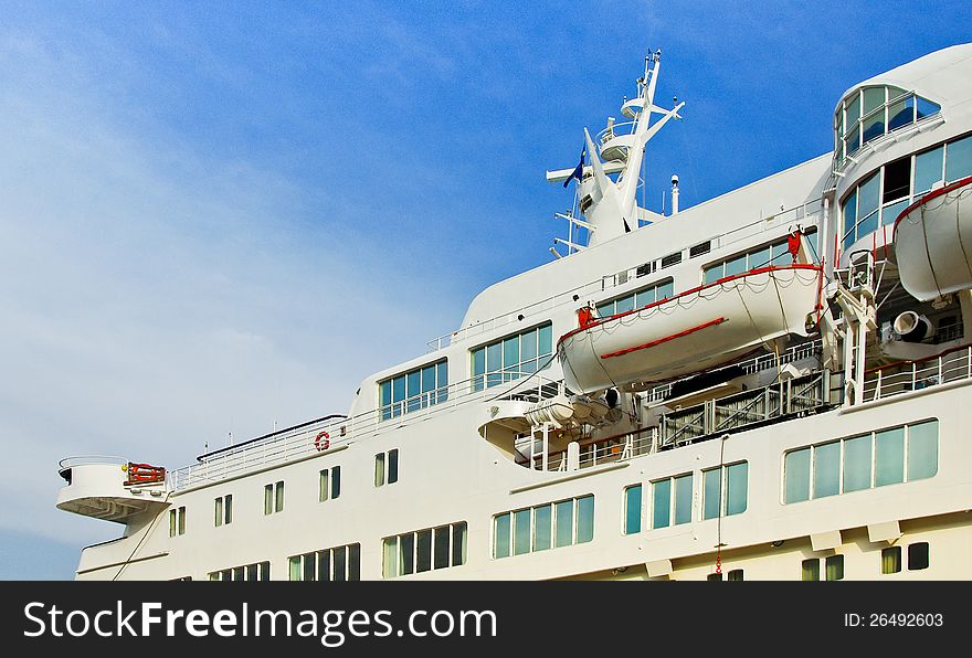 White cruise liner with portholes mooring in the sea port. Luxury cruise ship at blue sky background. Ocean liner with perspective view.