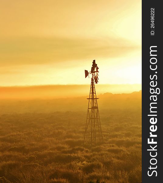 Landscape with Windmill water pump at sunrise