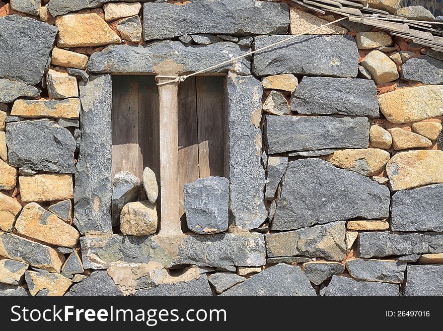 Rough window surrounded by a wall of stones