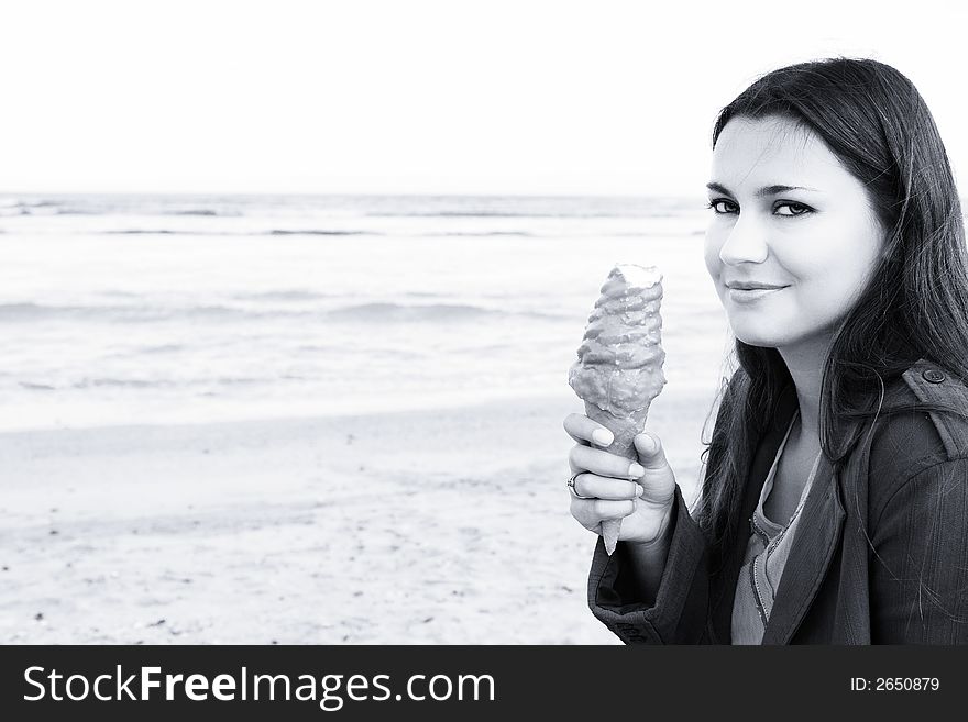 Beautiful woman with long dark hair smiling with ice-cream on beach, blue sepia. Beautiful woman with long dark hair smiling with ice-cream on beach, blue sepia