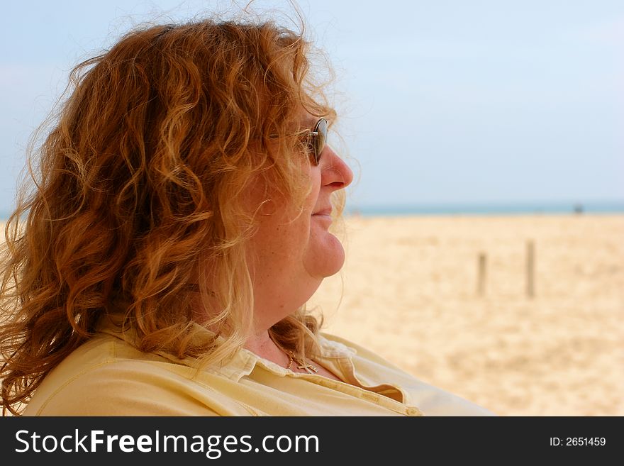 A Lady in sunglasses soaks up the sun at the baech. A Lady in sunglasses soaks up the sun at the baech