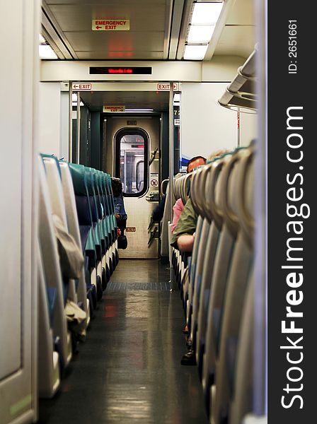A row of seats and passengers inside a commuter train cabin. A row of seats and passengers inside a commuter train cabin