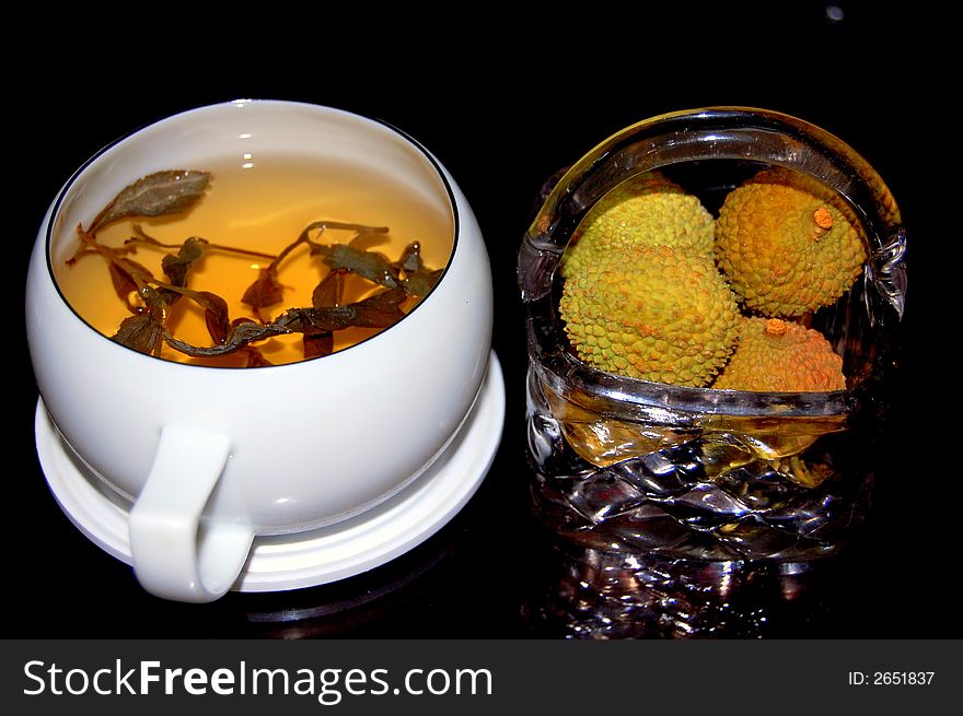 A cup of black tea and a basket of litchi. A cup of black tea and a basket of litchi