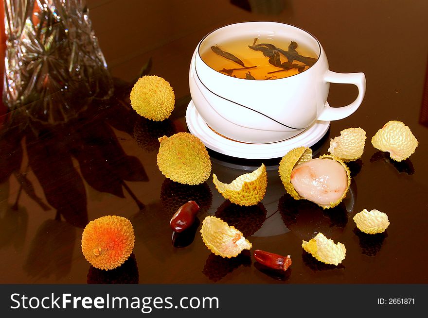 A cup of black tea and some litchi fruits. A cup of black tea and some litchi fruits