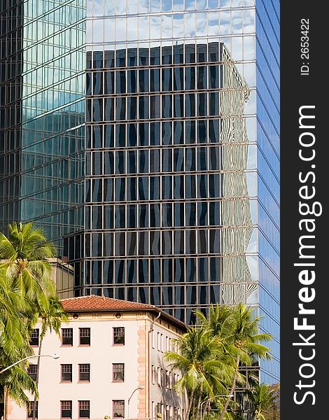 A building reflection of another building while dwarfing a neighboring building. A building reflection of another building while dwarfing a neighboring building