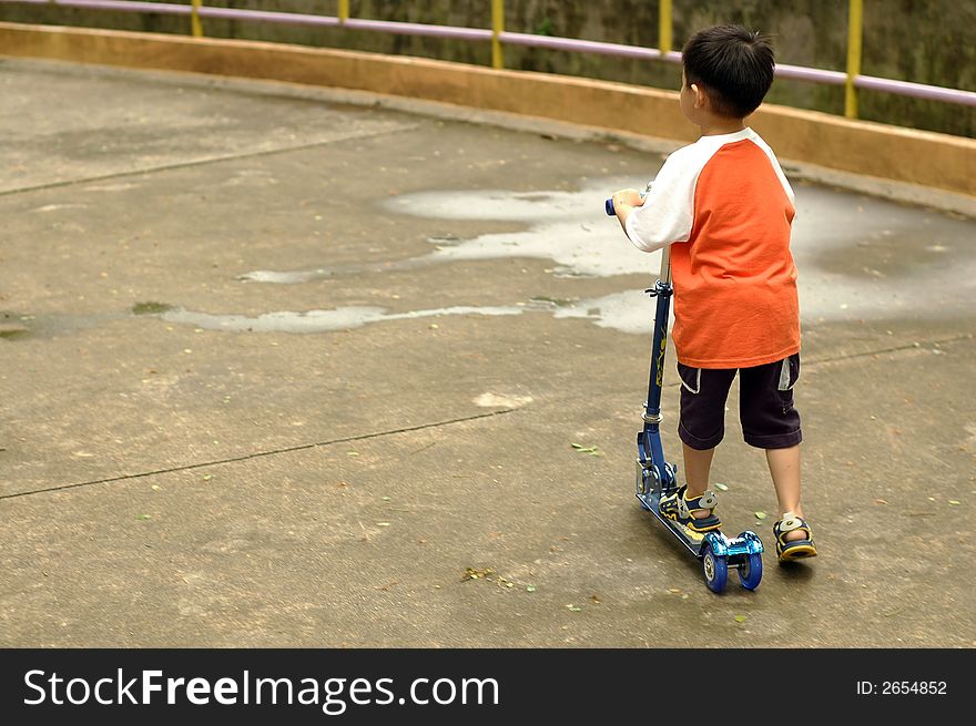 An asian kid playing toy scooter at park. An asian kid playing toy scooter at park