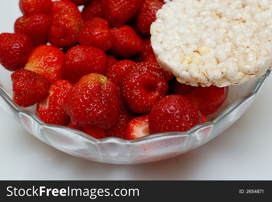 Glass bowl of fresh red strawberries and slice of corn bread. Glass bowl of fresh red strawberries and slice of corn bread.