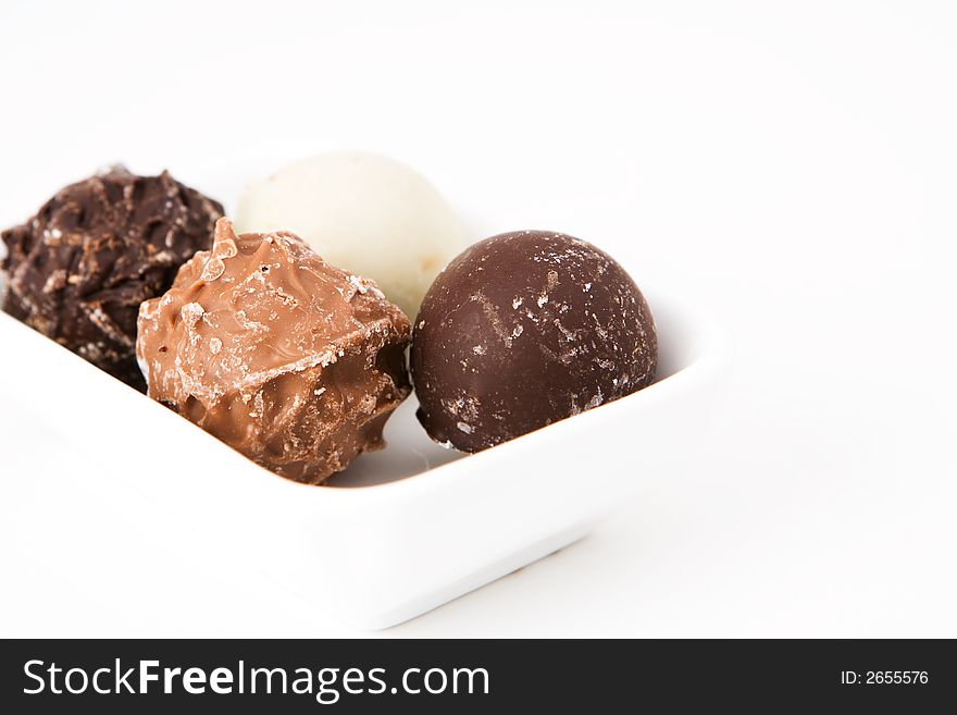 Four chocolate truffles in a white dish