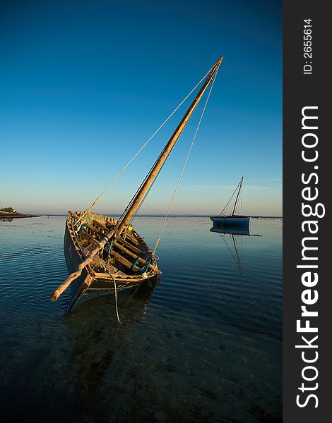 Two dhows waiting in the water during low tide.