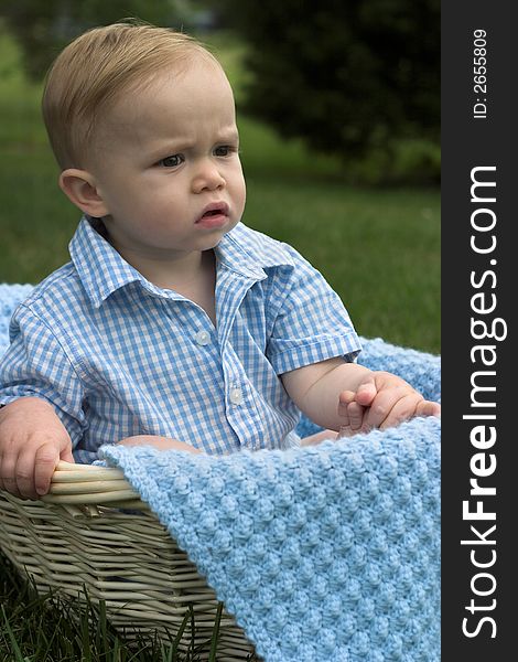 Image of beautiful toddler sitting in a basket in the grass. Image of beautiful toddler sitting in a basket in the grass