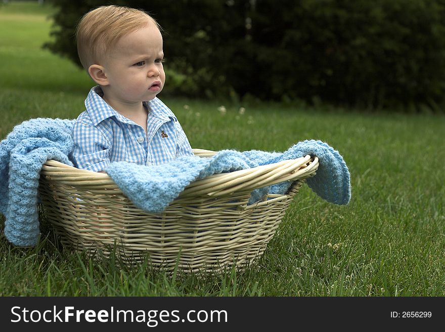 Image of beautiful toddler sitting in a basket in the grass. Image of beautiful toddler sitting in a basket in the grass