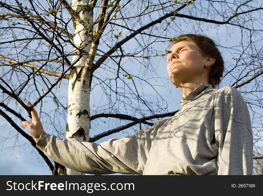 Woman and birch tree with leaves is expanding. Woman and birch tree with leaves is expanding