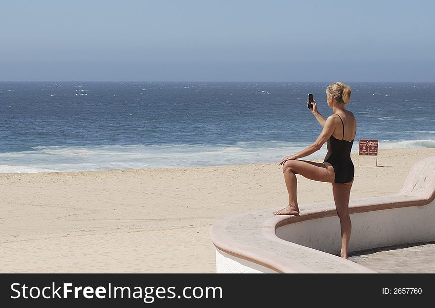 Woman taking a picture with a mobile phone of an empty beach in Cabo San Lucas, Mexico. Woman taking a picture with a mobile phone of an empty beach in Cabo San Lucas, Mexico.