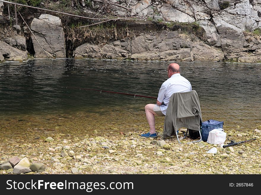 A man is fishing in a river in Asturias. A man is fishing in a river in Asturias