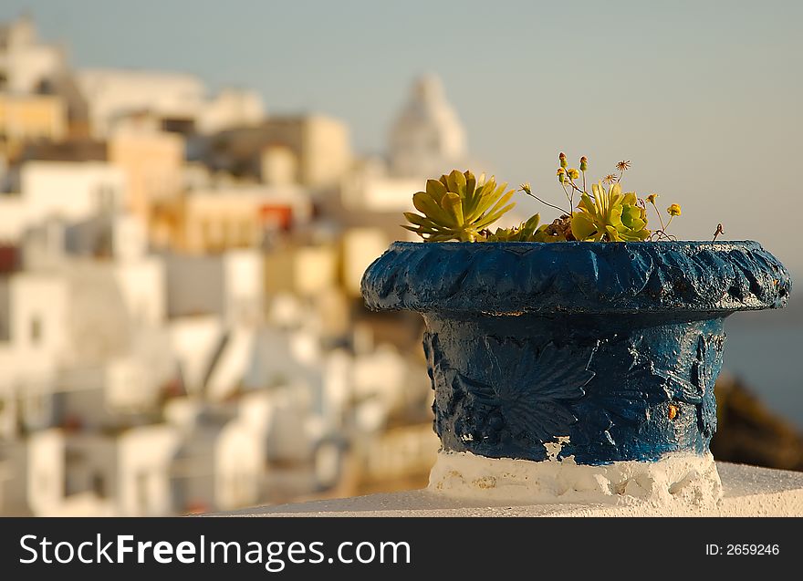 Blue plant pot on the island of Santorini, Greece. The town of Fira appears in the background. Blue plant pot on the island of Santorini, Greece. The town of Fira appears in the background