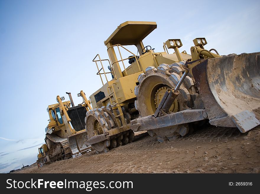 Two bulldozers parked on a construction site. Two bulldozers parked on a construction site.