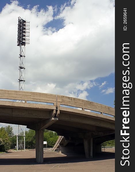 Stadium searchlirht and road on blue sky with clouds