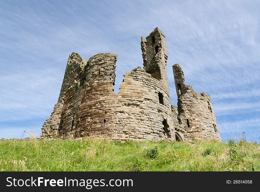 Iconic Dunstanburgh castle ruin built in the 14th century viewed from below the hill close up. Iconic Dunstanburgh castle ruin built in the 14th century viewed from below the hill close up