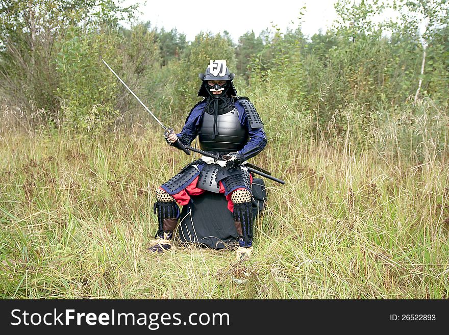 Man dressed in Japanese armor of the XVI century holding long sword katana. Man dressed in Japanese armor of the XVI century holding long sword katana