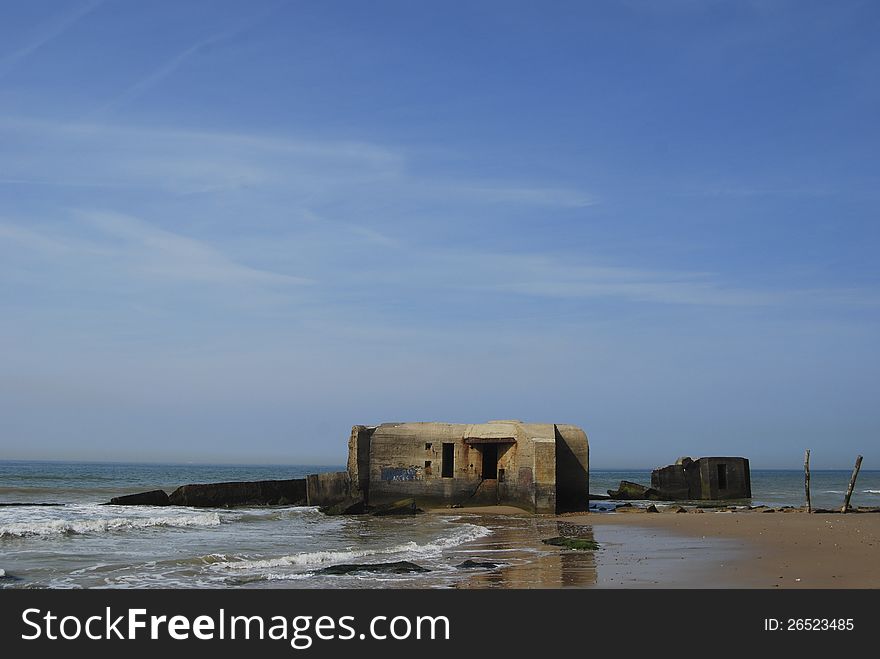 Under a blue sky there are on a French beach two German bunkers from Second World II. Under a blue sky there are on a French beach two German bunkers from Second World II