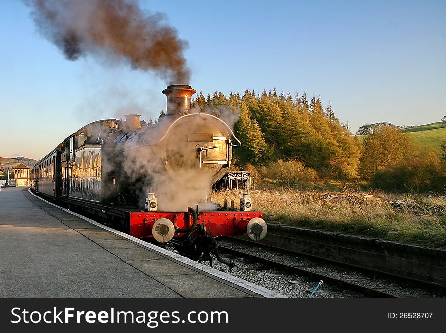 Steam railway engine billows steam and smoke whilst waiting at a station. Steam railway engine billows steam and smoke whilst waiting at a station